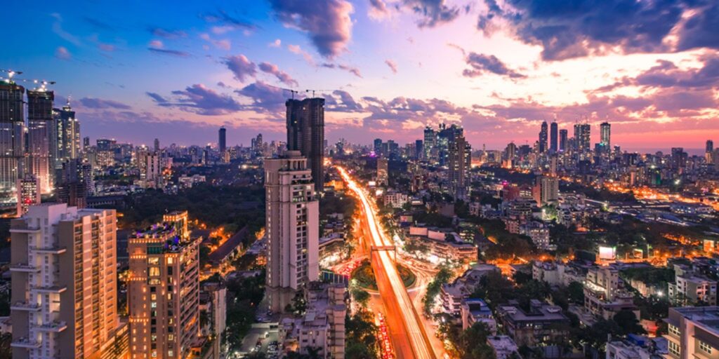 रात के समय महानगर का रोशन दृश्य, तेज़ रफ्तार यातायात और ऊँची इमारतें