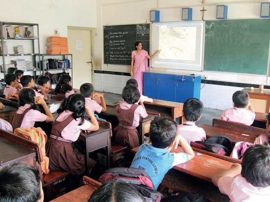 कक्षा में पढ़ाती शिक्षिका और ध्यानपूर्वक अध्ययन करते स्कूली छात्र