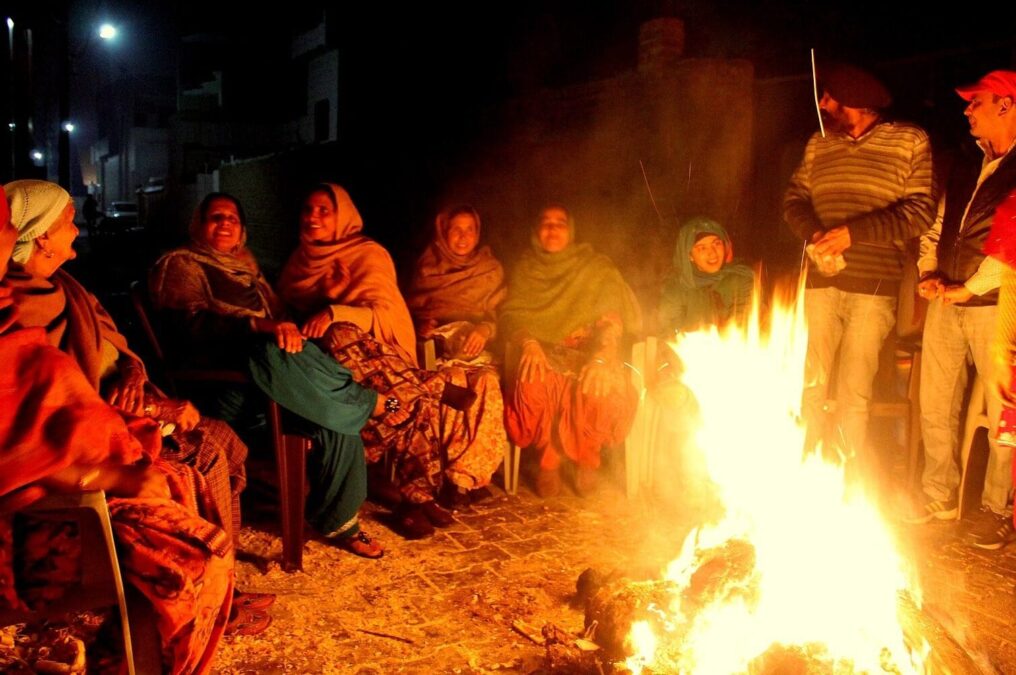 सर्दी की रात में आग के चारों ओर बैठे लोग, मकर संक्रांति के मौसम में सामूहिक जीवन और ऋतु परिवर्तन का प्रतीक